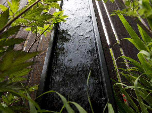 Fontaine verticale encadrée de bois noir.