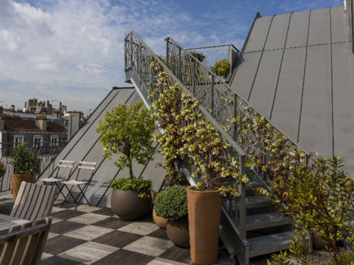 Escalier menant à la terrasse en bois, du premier niveau, orné de jasmin blanc, d'une véronique, d'un calamondin et un pachysandre.